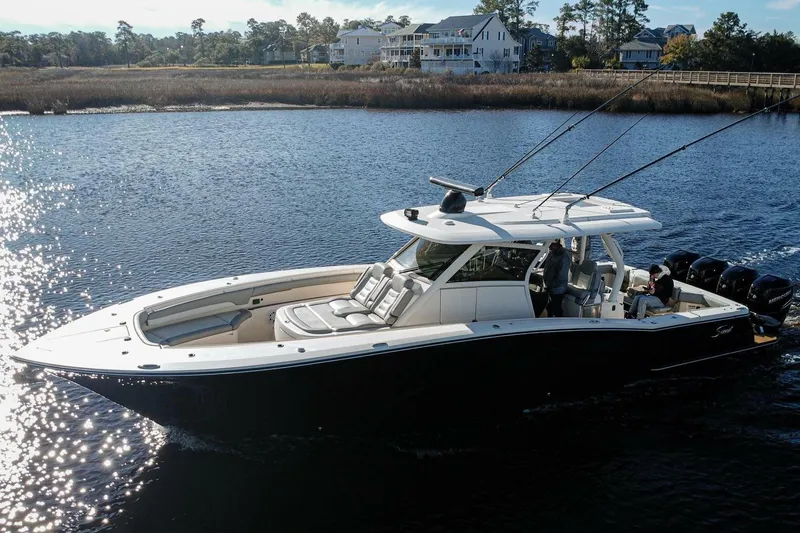 The Image of 2020 Scout 380 LXF boat cruising on a serene lake near waterfront homes. - 0