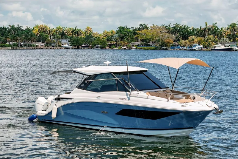Slide: The Image of 2022 Sea Ray Sundancer 320 Outboard cruising on a scenic lake with palm trees. - 5
