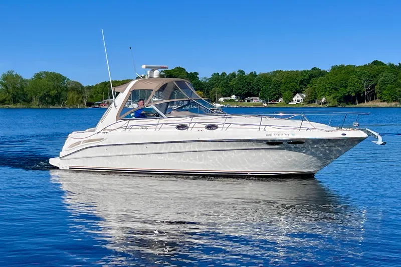 The Image of 2000 Sea Ray 340 Sundancer cruising on a serene lake under a clear blue sky. - 3