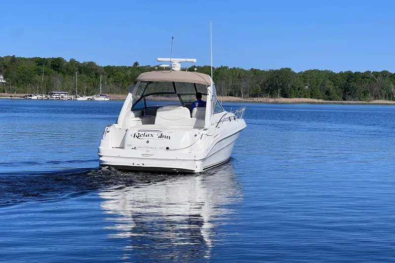 Slide: The Image of 2000 Sea Ray 340 Sundancer cruising on a serene lake with lush green shoreline. - 6