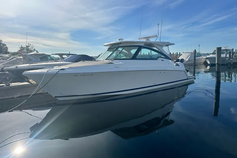 The Image of 2021 Tiara Yachts 34 LX docked in a marina under a clear blue sky. - 0