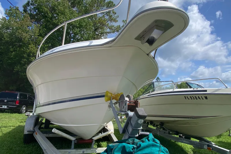 Slide: The Image of 2001 Aquasport 215 Osprey Sport boat on trailer, parked outdoors under blue sky. - 4