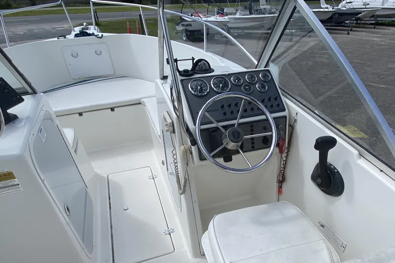 Slide: The Image of 2001 Aquasport 215 Osprey Sport boat cockpit with steering wheel and control panel. - 7
