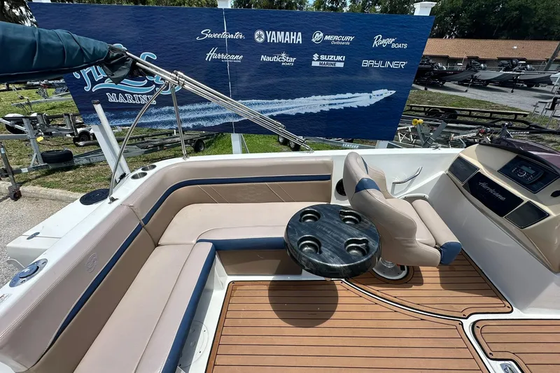 Slide: The Image of 2019 Hurricane Sundeck Sport 218 OB boat interior with seating and table, displayed at a marina. - 27