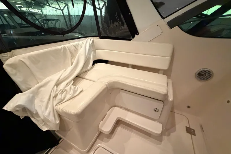 Slide: The Image of 2004 Tiara Yachts 3200 Open interior seating with white upholstery and storage compartment. - 12