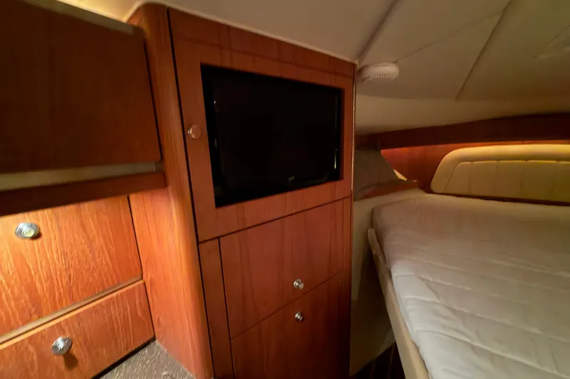 Slide: The Image of Interior of 2004 Tiara Yachts 3200 Open, featuring wood cabinetry and a cozy bed. - 27