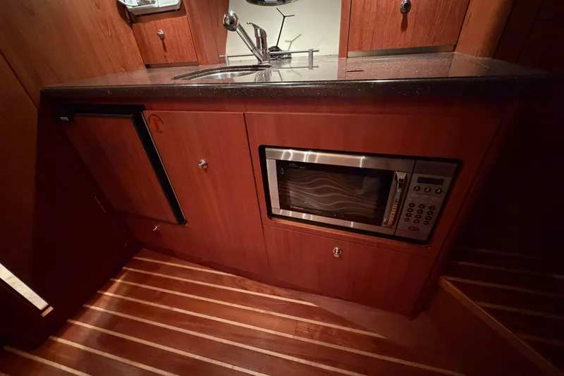 Slide: The Image of 2004 Tiara Yachts 3200 Open galley with microwave, sink, and wooden cabinetry. - 29