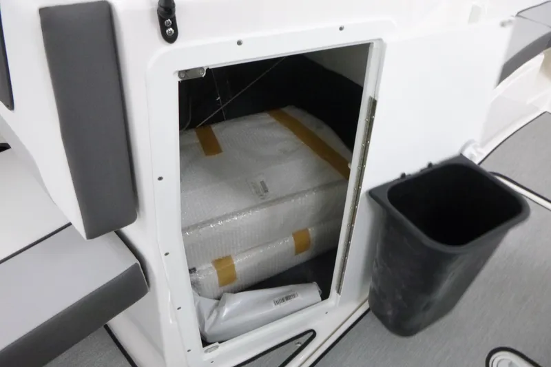 Slide: The Image of Storage compartment of 2026 Yamaha Boats AR220, featuring interior packaging and adjacent trash bin. - 11