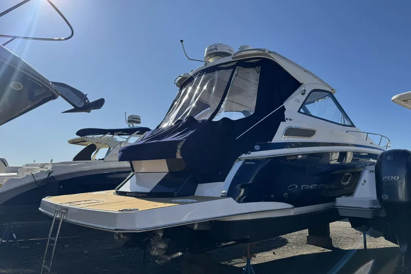 Slide: The Image of 2016 Regal 35 Sport Coupe boat with covered cockpit, docked under clear blue sky. - 5