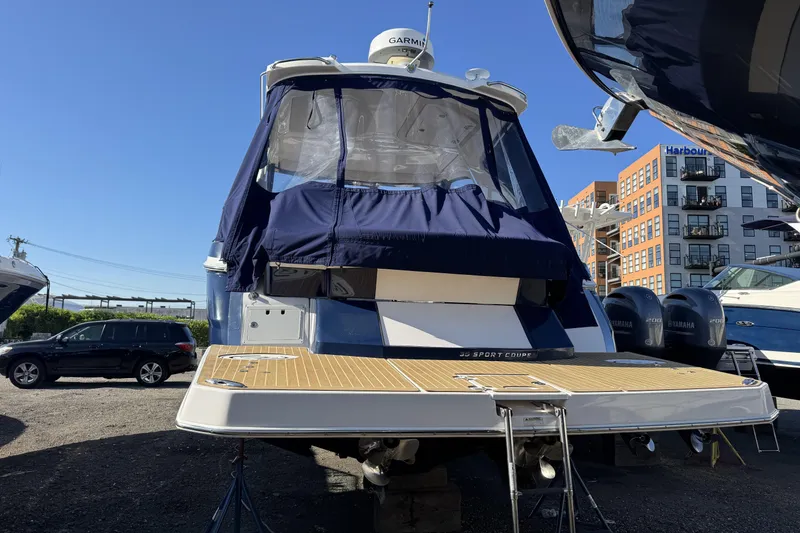 Slide: The Image of 2016 Regal 35 Sport Coupe boat with blue canopy, docked outdoors. - 6