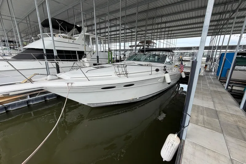 The Image of 1994 Sea Ray Sundancer 330 docked in a marina under a covered structure. - 1