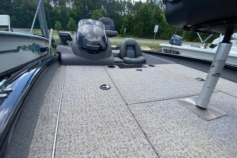 Slide: The Image of 2020 Tracker Pro Team 175 TXW boat interior with seating and console, parked outdoors. - 9