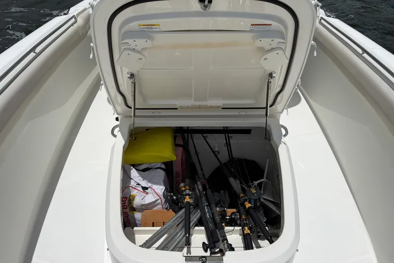 Slide: The Image of Open storage compartment on 2020 Boston Whaler 330 Outrage, containing fishing rods and gear. - 10