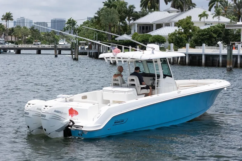 Slide: The Image of 2020 Boston Whaler 330 Outrage boat cruising near a marina with palm trees. - 16