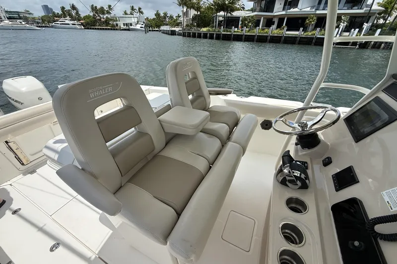 Slide: The Image of 2020 Boston Whaler 330 Outrage boat interior with helm and seating by the water. - 5