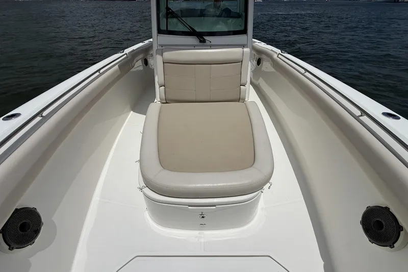 Slide: The Image of 2020 Boston Whaler 330 Outrage boat interior with cushioned seating on calm water. - 7