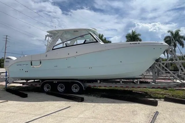 The Image of 2023 World Cat 325 DC boat on trailer, parked outdoors under cloudy sky. - 1
