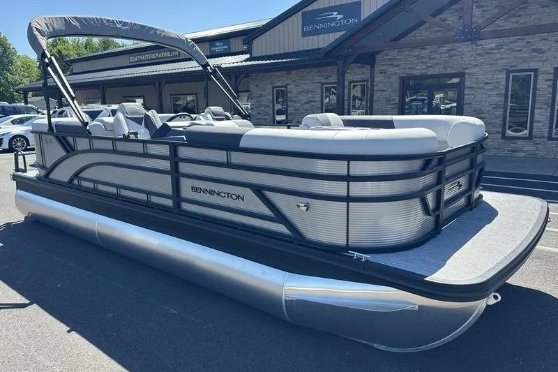 Slide: The Image of 2026 Bennington 22 S Quad Bench pontoon boat parked outside dealership. - 2