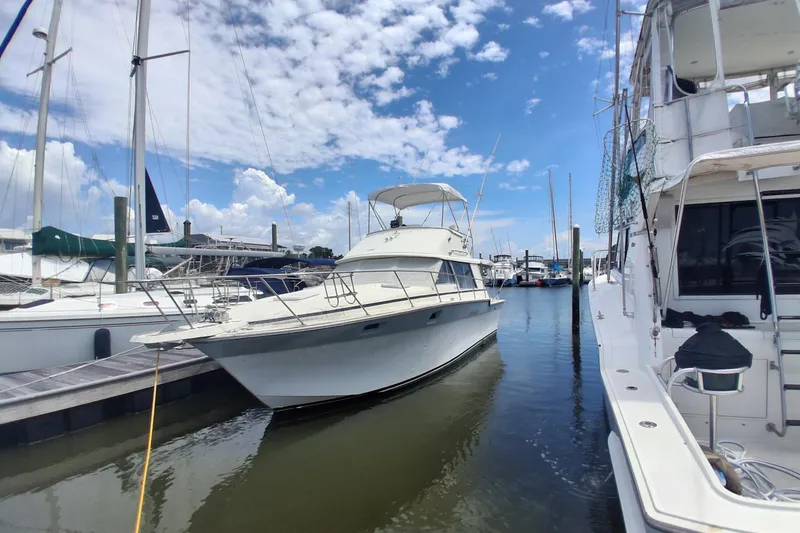 The Image of 1986 Silverton 34 Convertible yacht docked at a marina under a partly cloudy sky. - 0