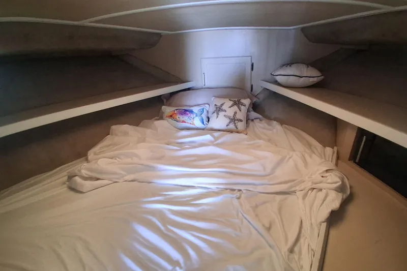 Slide: The Image of Cozy cabin interior of 1986 Silverton 34 Convertible with white bedding and decorative pillows. - 15