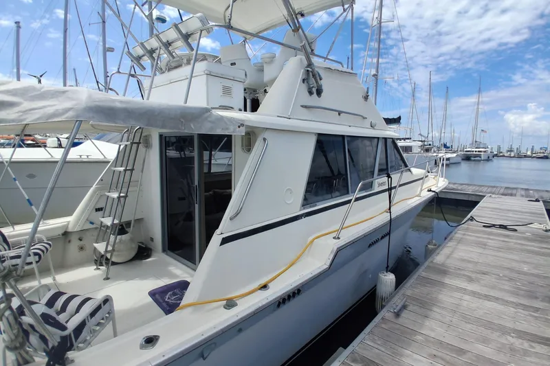 Slide: The Image of 1986 Silverton 34 Convertible yacht docked at marina under blue sky. - 2