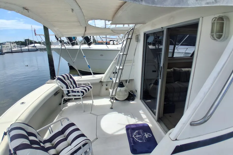 Slide: The Image of 1986 Silverton 34 Convertible yacht with striped seating, docked at a marina. - 3