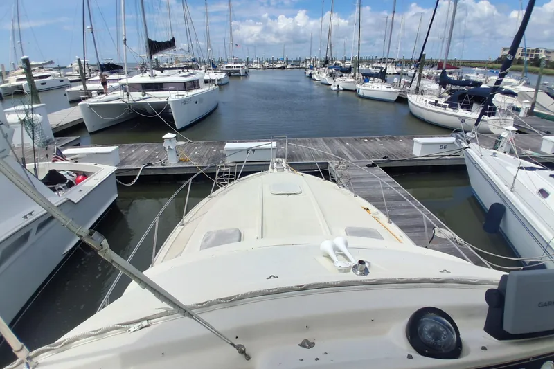 Slide: The Image of 1986 Silverton 34 Convertible docked at a marina with sailboats and clear skies. - 4