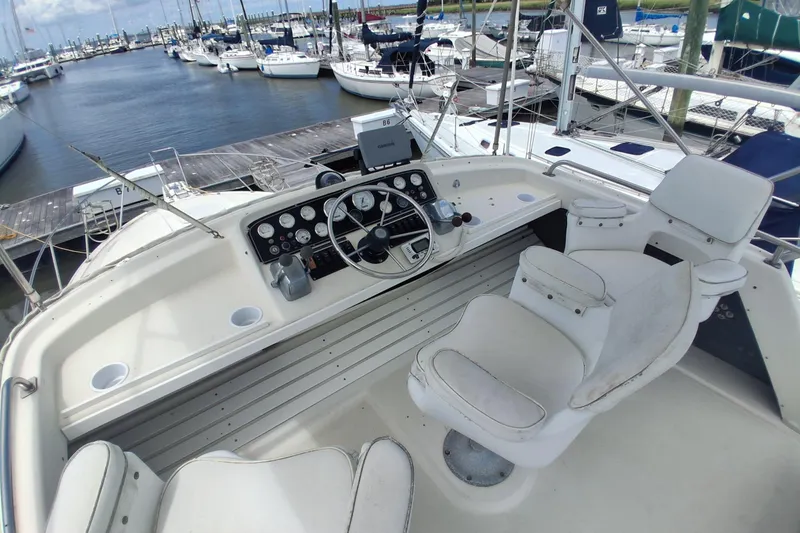 Slide: The Image of 1986 Silverton 34 Convertible boat helm with white seating at marina. - 5