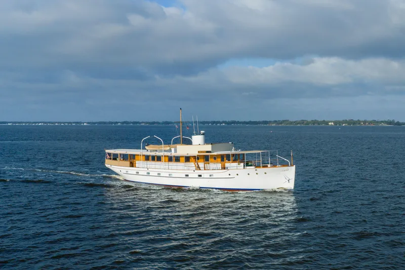 The Image of 1939 Mathis Trumpy Fantail Houseboat cruising on open water under cloudy skies. - 0