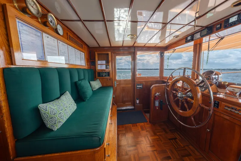 Slide: The Image of 1939 Mathis Trumpy Fantail Houseboat interior with wooden helm and green seating. - 18