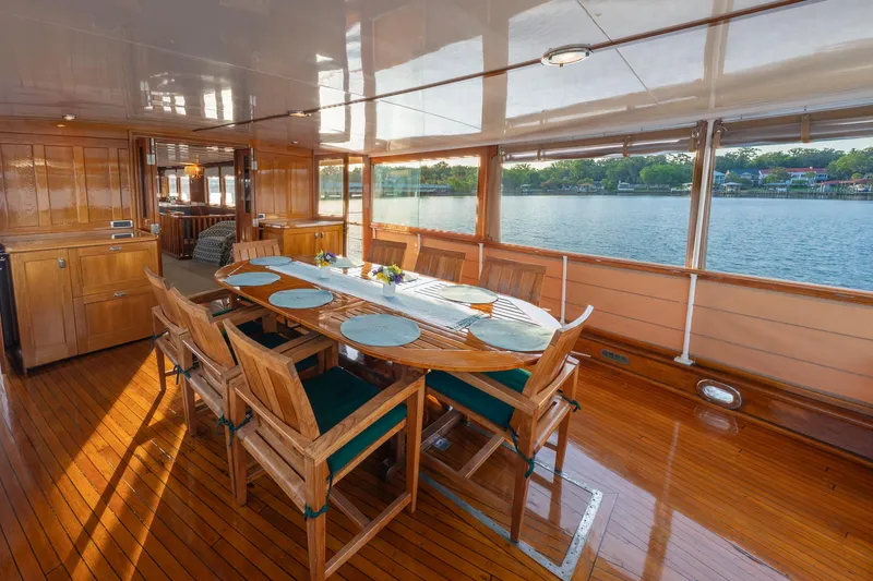 Slide: The Image of Elegant dining area on 1939 Mathis Trumpy Fantail Houseboat with wooden furniture and scenic water view. - 31