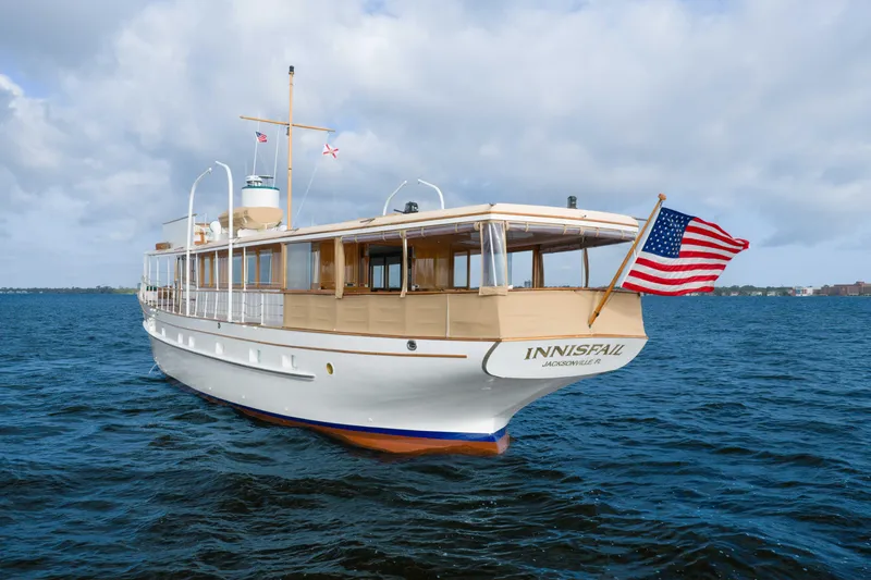 Slide: The Image of 1939 Mathis Trumpy Fantail Houseboat on water, American flag, cloudy sky. - 43