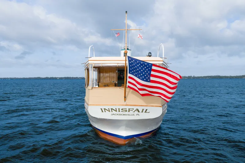 Slide: The Image of 1939 Mathis Trumpy Fantail Houseboat "Innisfail" on water, American flag waving. - 44