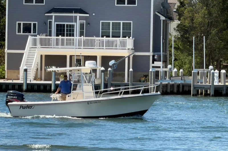 The Image of 2006 Parker 23SE Center Console boat cruising near waterfront home. - 0