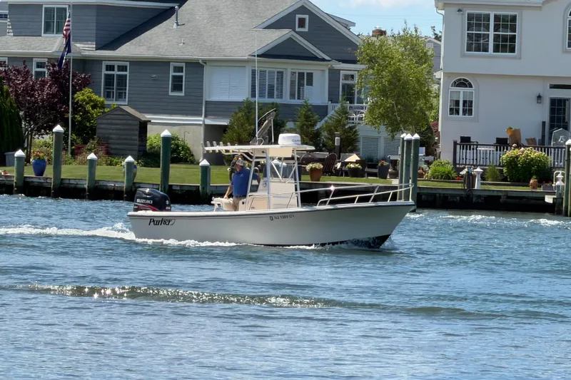 Slide: The Image of 2006 Parker 23SE Center Console boat cruising near waterfront homes. - 2