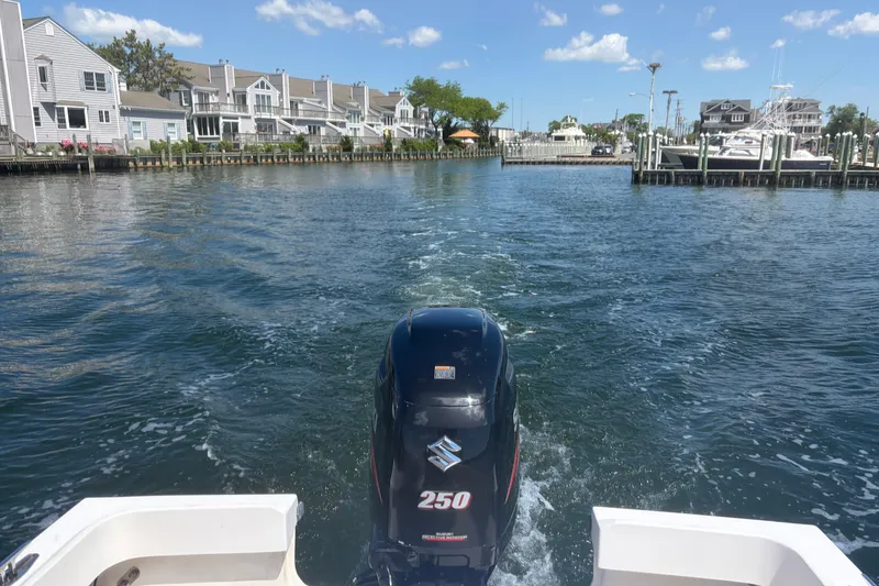 Slide: The Image of 2006 Parker 23SE Center Console boat cruising in a scenic waterfront neighborhood. - 5