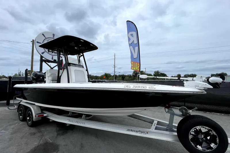 The Image of 2019 ShearWater 25 LTZ boat on trailer, displayed outdoors under cloudy sky. - 0