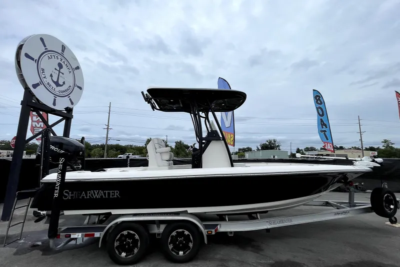 Slide: The Image of 2019 ShearWater 25 LTZ boat on trailer at dealership with sale banners. - 1