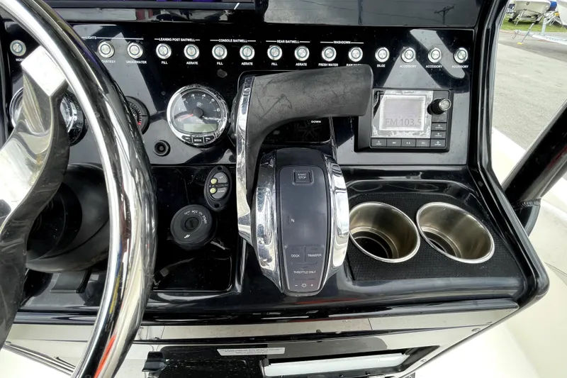 Slide: The Image of 2019 ShearWater 25 LTZ boat dashboard with controls, gauges, and cup holders. - 25