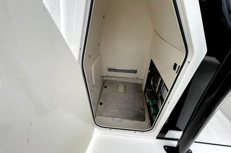Slide: The Image of 2019 ShearWater 25 LTZ boat interior storage compartment with visible wiring and carpeted floor. - 29