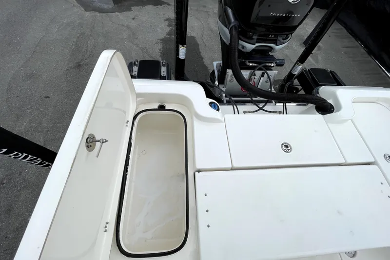 Slide: The Image of 2019 ShearWater 25 LTZ boat deck with open storage compartment and motor. - 48
