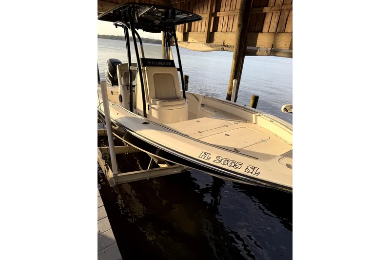 The Image of 2019 ShearWater 25 LTZ boat docked under a wooden shelter. - 1
