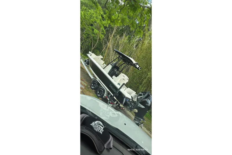 Slide: The Image of 2019 ShearWater 25 LTZ boat on trailer, surrounded by lush greenery. - 3