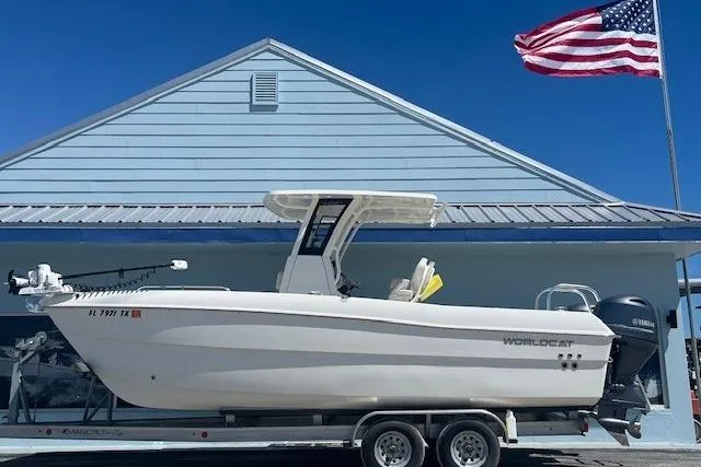 The Image of 2025 World Cat 235 TE boat on trailer, parked by a building with an American flag. - 1