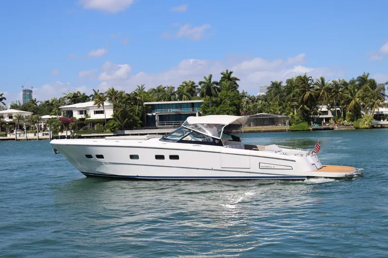 The Image of Luxury CNM 50 yacht cruising on a sunny day, surrounded by palm trees and waterfront homes. - 1