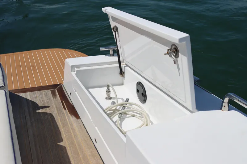 Slide: The Image of Open storage compartment on CNM 50 boat, featuring hose and wooden deck, 2010 model. - 12