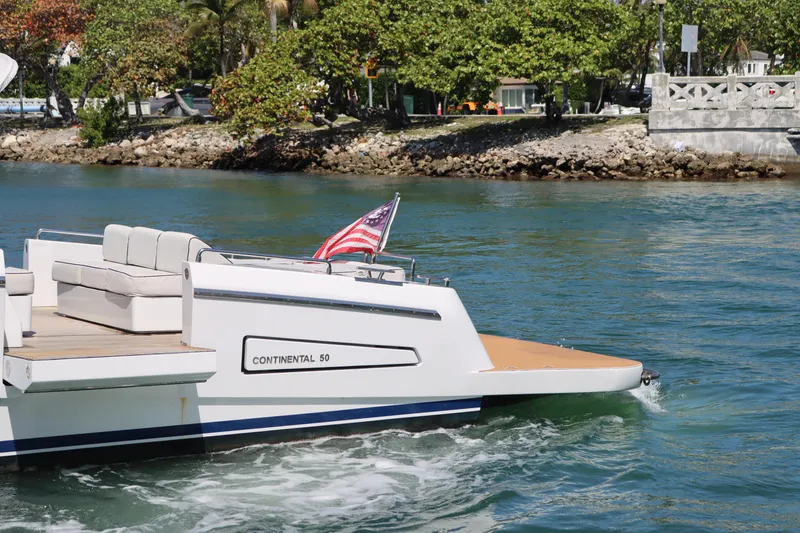 Slide: The Image of Luxury CNM Continental 50 yacht cruising near lush shoreline, featuring elegant seating and American flag. - 7