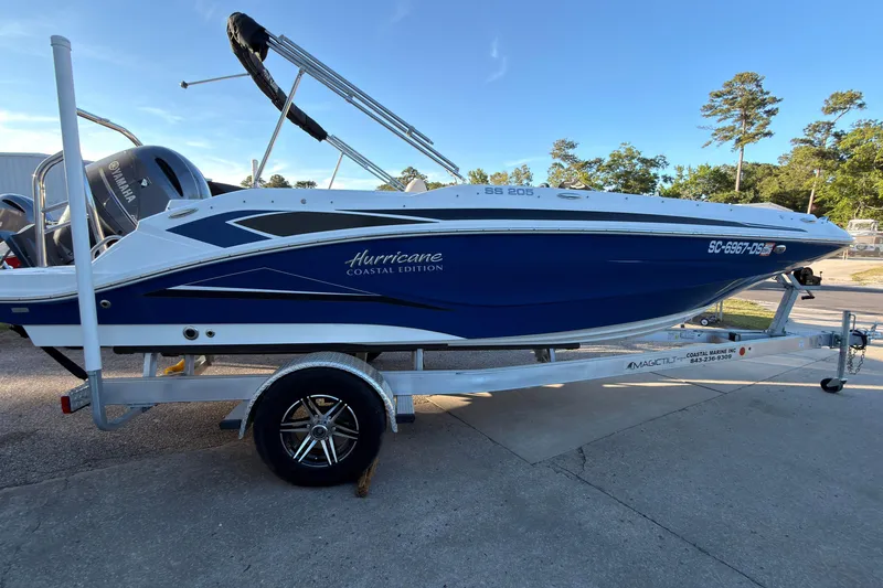 The Image of 2022 Hurricane SunDeck Sport 205 OB boat on trailer, blue and white design, parked outdoors. - 0