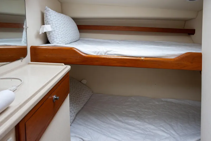 Slide: The Image of Bunk beds in 2000 Cabo 45 Express yacht cabin with wooden accents and white bedding. - 4