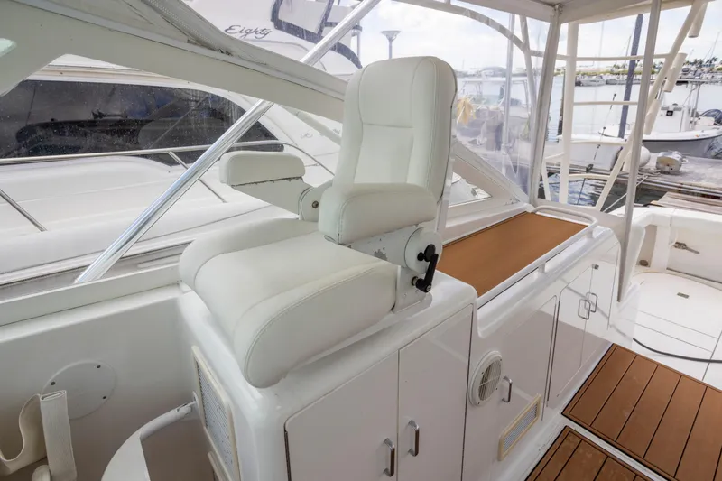 Slide: The Image of Captain's chair on 2000 Cabo 45 Express yacht, featuring sleek white design and wood accents. - 8